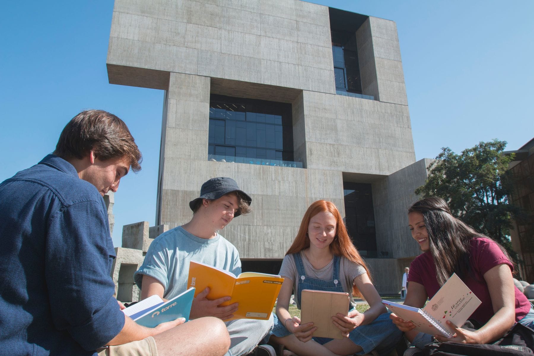 http://Vista%20de%20un%20edificio%20moderno%20en%20un%20campus%20universitario%20con%20estudiantes%20leyendo%20en%20primer%20plano.